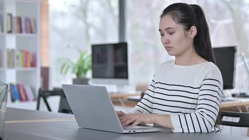Laptop Use By Young Asian Woman Looking at Camera in Office