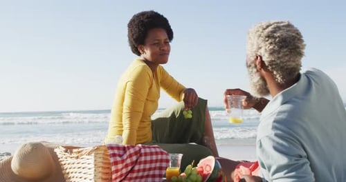 Happy african american couple having picnic on sunny beach