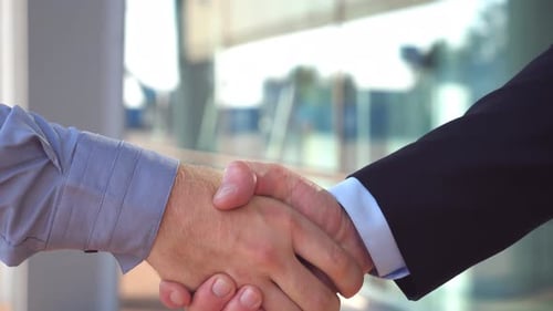 Two Young Colleagues Shaking Hands After Successful Deal Near Office Building. Confident Businessmen