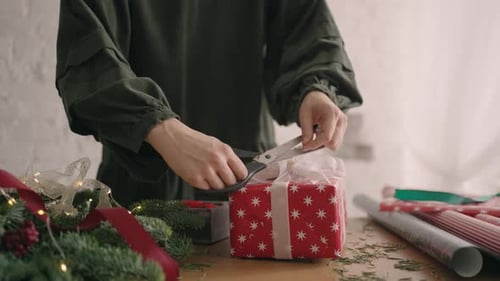 Woman Finishing Wrapping Christmas Present in Bright Room