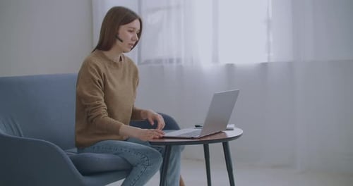 Young Woman Working at Computer with Headset at Home