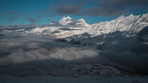 Majestic Snow Mountains Emerging Through Clouds