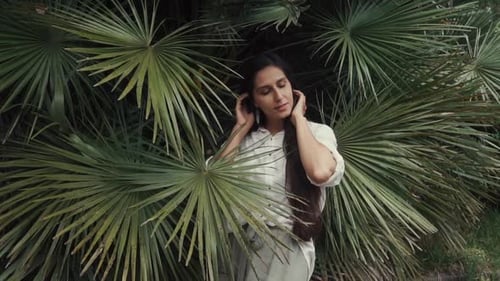 Woman with Long Hair Posing by Tropical Leaves