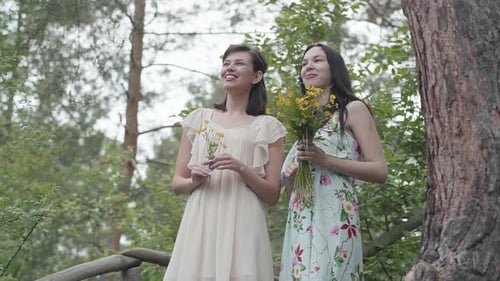 Two Women with Flowers Standing on Bridge