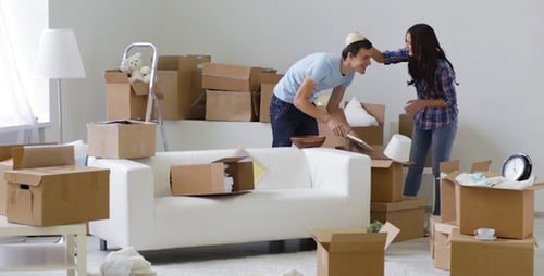 Couple Unpacks Boxes in Bright Room