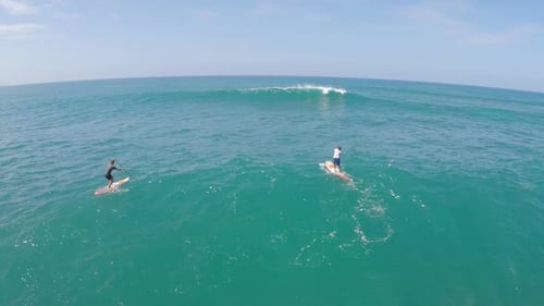 Aerial view of two men sup stand-up paddleboard surfing in Hawaii.