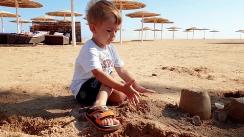 Footage of Little Toddler Boy Playing with Wet Sand on the Sea Beach