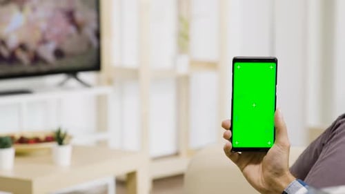 Holding Vertically a Green Screen Phone in Hands in Modern and Well Lit Living Room