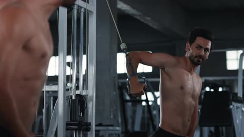 4K Caucasian man bodybuilder pulling weight lifting machine at gym.