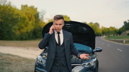 Young Man Talks on Phone by Broken Down Car