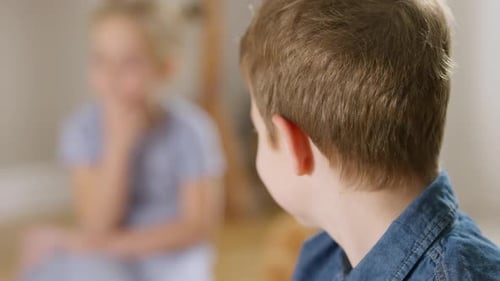 Portrait d'un mignon garçon brun caucasien confiant aux yeux bleu-gris regardant en arrière une fille floue