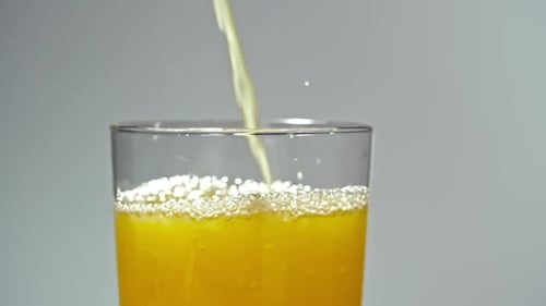 Yellow Beverage Being Poured Into Clear Glass