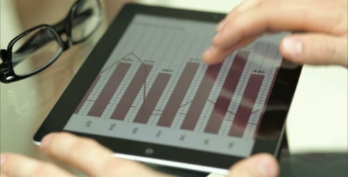 Man uses tablet with graphs and charts