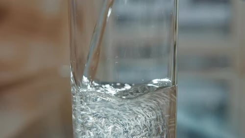 Mineral Water Is Poured Into a Glass From the Bottle Close Up, Moving Camera