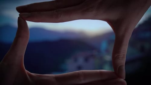 Hands Framing Rural Landscape at Sunset