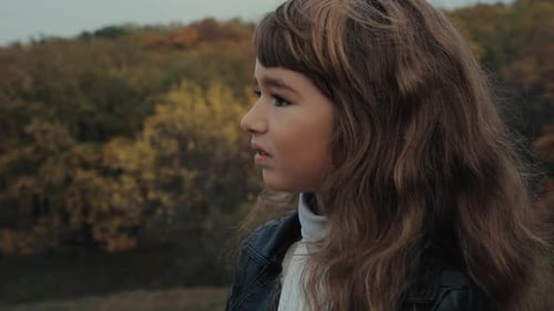 Une petite fille regarde autour d'elle un jour d'automne