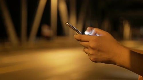 Hands Using Phone at Night in City