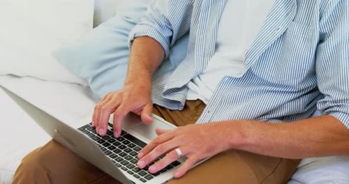 Adult Typing on Laptop on Couch Indoors
