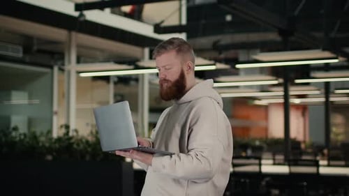 Bearded Guy Using Laptop Computer Working Online Standing In Office