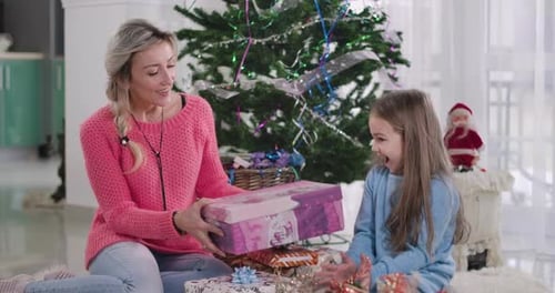 Mother and Daughter Exchanging Gifts by Christmas Tree