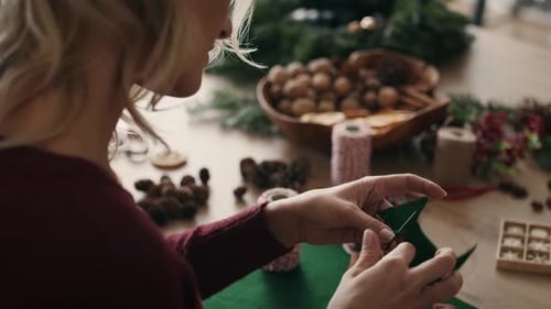 Woman Crafts Christmas Ornament With Needle and Thread