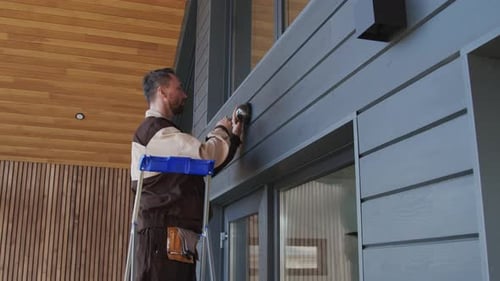 Man Installing Security Camera on Modern Home Exterior