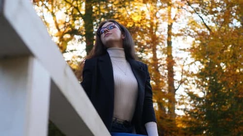 Young Woman in Casual Outfit Sitting on Fence at Public Park on Autumn Day, Slow Motion of Teenage G