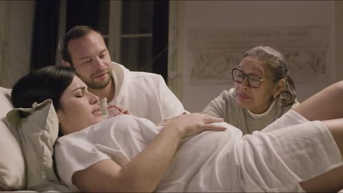 Schwangere Frau liegt auf dem Bett im Schlafzimmer und hat Kontraktionen