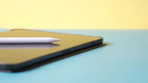 Tablet and Stylus Resting on Blue Surface