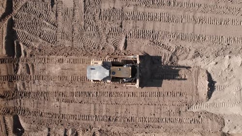 Tracking Drone Shot of Crawler Bulldozer Working on Construction Site or Quarry