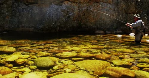 Fisherman fly fishing in river