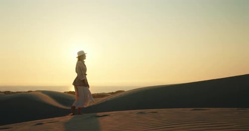 Woman Walking on Sand Dune at Sunset