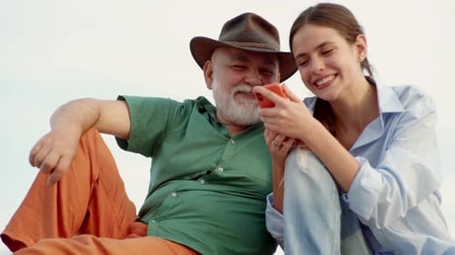 Smiling Woman and Senior Man Looking at Cellphone