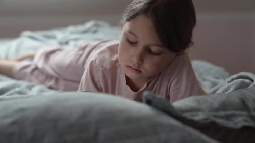 Girl Lies on Bed Looking at Phone