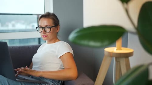 Woman Using Laptop While Sitting on Couch