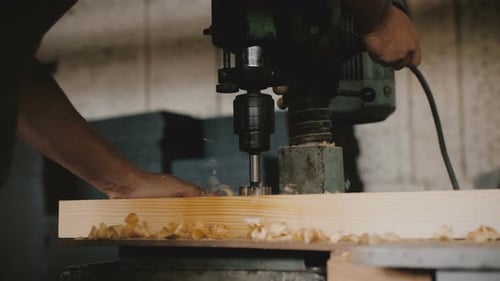 Close-up Male Hands Drilling Wood Plank with Professional Machine Tool at a Factory. Carpenter Man