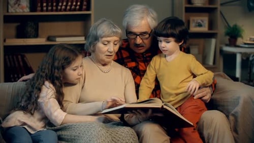 Family Reading Book Together on Couch Indoors