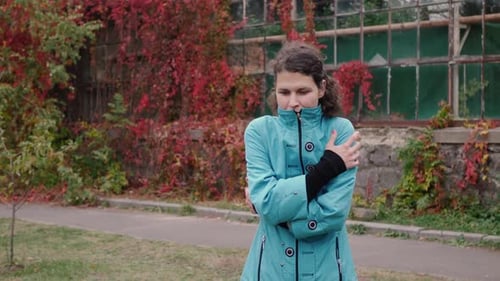 Woman Rubbing Arms Outside in Cold Autumn Weather
