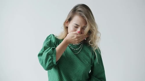 Slow Motion Portrait of Sick Young Woman Sneezing and Wiping Nose on White Background