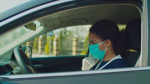 Woman in Car Sanitizing Hands and Steering Wheel