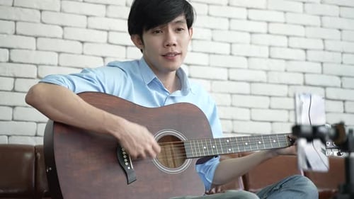 Young Adult Plays Guitar and Sings a Song