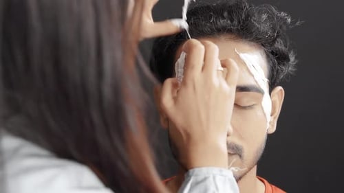Applying Cream to Young Adult Man's Face