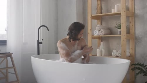 Man Washing in a Bubble Bath with Sponge