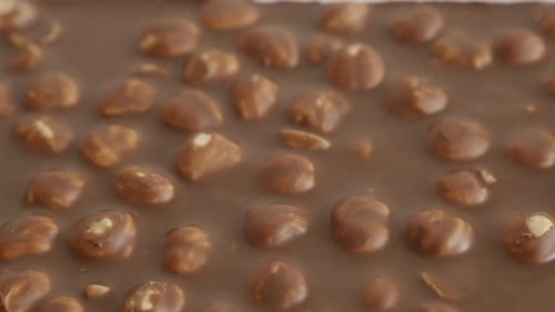 Close-up of milk chocolate with whole hazel nuts slow tilt 4K 2160p 30fps UltraHD footage - Fine tex