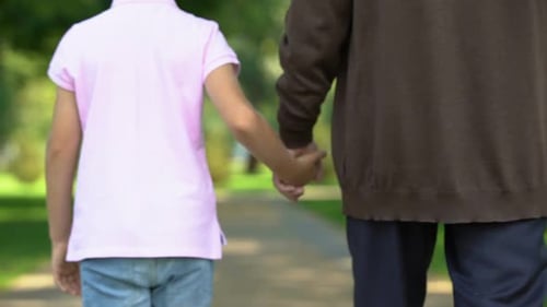Boy and Senior Man Walking Hand in Hand