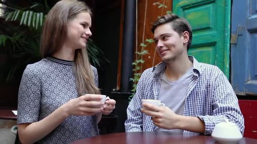 Couple In Cafe. Young People Drinking Coffee And Communicating