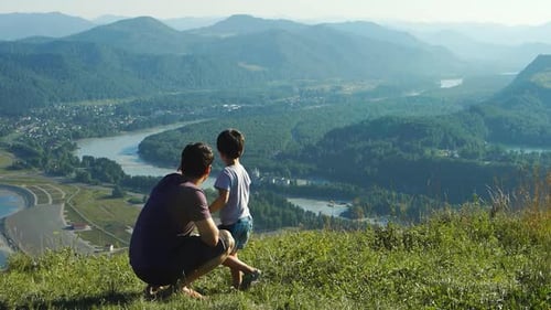 Vater mit Sohn blickt auf die Berge und den Fluss