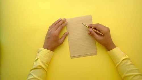 Man Hand Writing on a Paper on Yellow Background