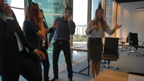 Colegas felizes comemorando aniversário no moderno escritório de coworking. Serpentina, tubos.