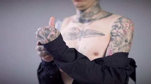 Tattooed Young Adult Putting on Black Shirt